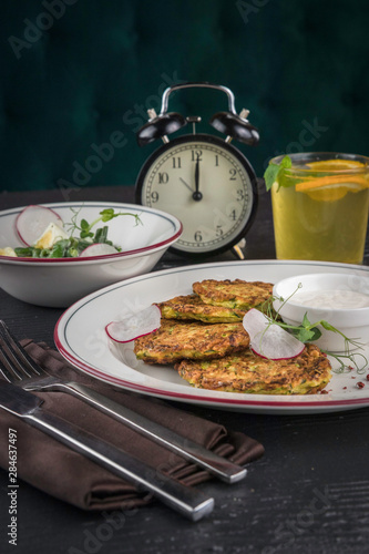 Potato pancakes on a white plate. Fresh vegetable salade and lemonade drink. Lunch time 12pm photo