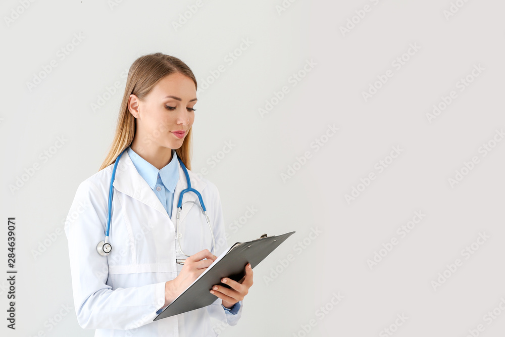 Female doctor with stethoscope and clipboard on light background Female doctor with stethoscope and clipboard on light background
