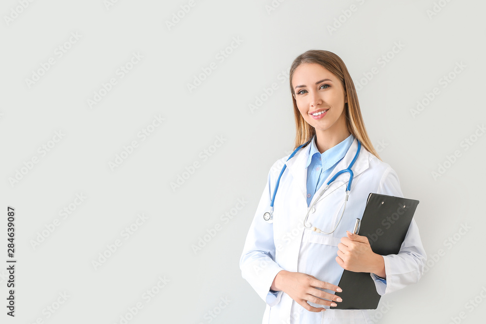 Female doctor with stethoscope and clipboard on light background Female doctor with stethoscope and clipboard on light background