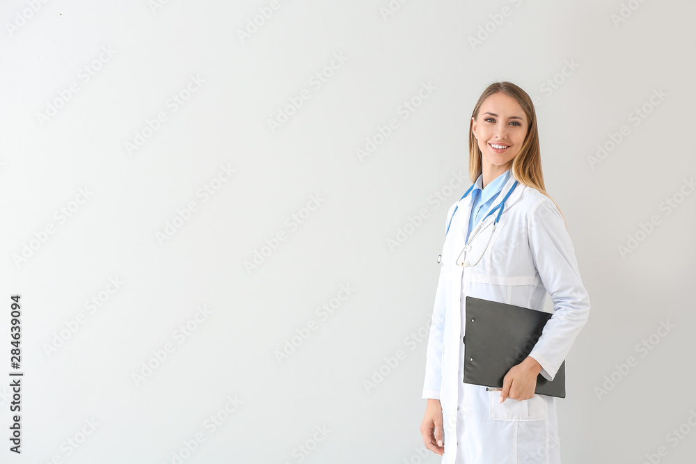 Female doctor with stethoscope and clipboard on light background Female doctor with stethoscope and clipboard on light background