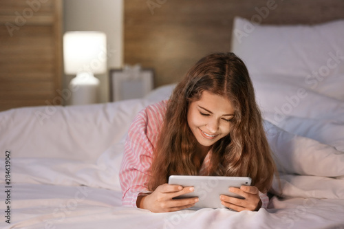 Teenage girl with tablet computer in bed at night