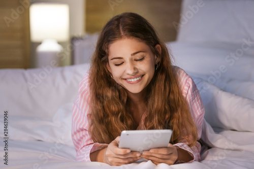 Teenage girl with tablet computer in bed at night