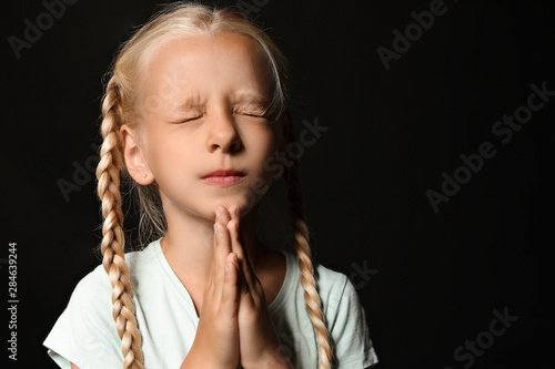 Little girl praying on dark...