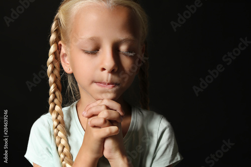 Little girl praying on dark...