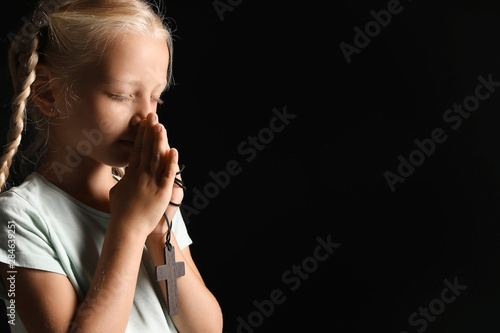 Little girl praying on dark...