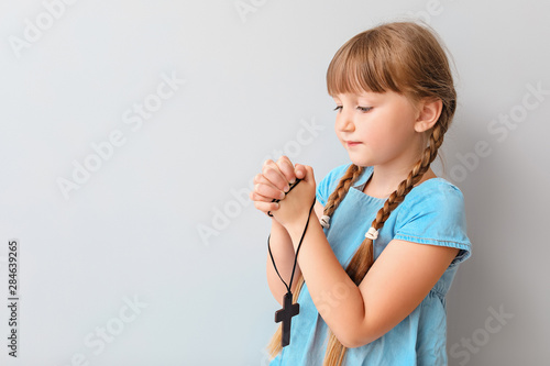 Little girl praying on light background
