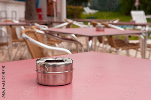 Steel ashtray on a table outside a hotel bar. photo