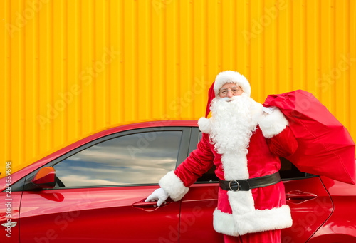 Santa Claus with gifts in bag near car outdoors © Pixel-Shot