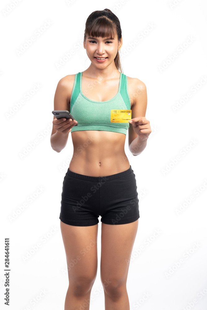 Fitness woman using mobile phone and holding credit card isolate in white background. Asian girl, holding card. Fitness woman using mobile phone and holding credit card isolate in white background. Asian girl, holding card.