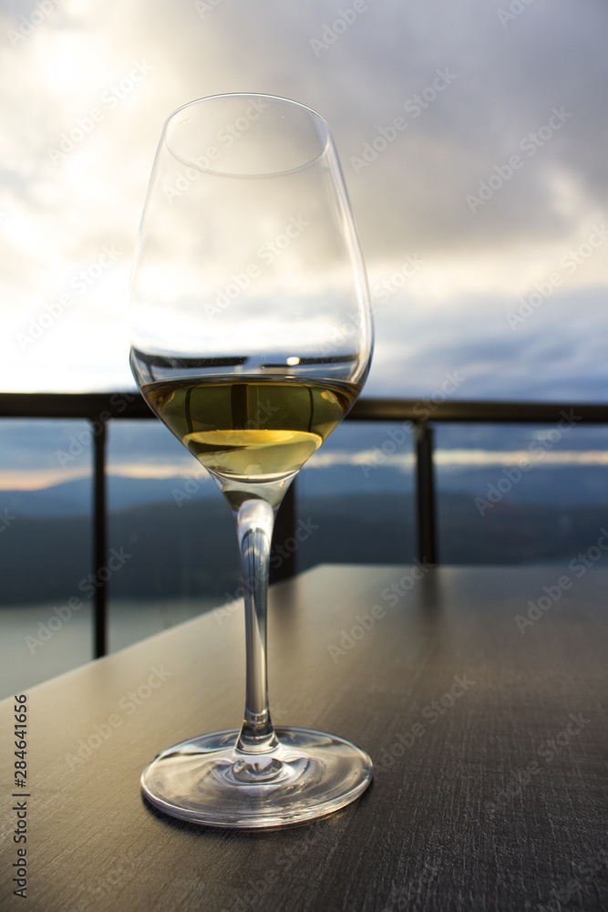 glass of white wine on restaurant outdoor table on background of blue sky