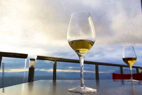 two glasses of white wine on reastaurant table on outdoor terrace with beutiful view
