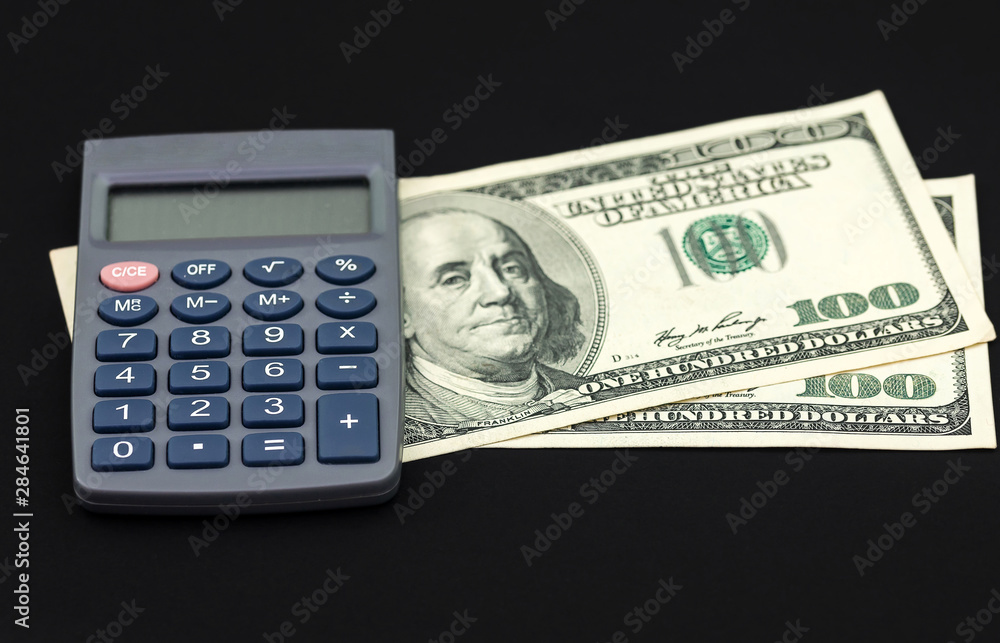 Two hundred dollar bills and calculator isolated on black background Two hundred dollar bills and calculator isolated on black background