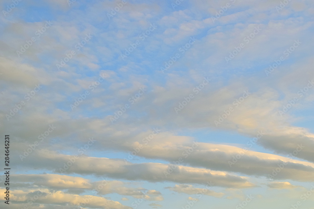 Ribbed clouds. Elongated clouds in the rays of the setting sun. Are highlighted in yellow light. Ribbed clouds. Elongated clouds in the rays of the setting sun. Are highlighted in yellow light.