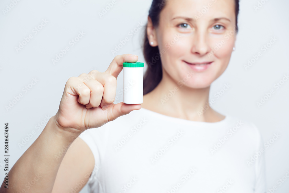 Woman holding white plastic pill bottle selective focus closeup