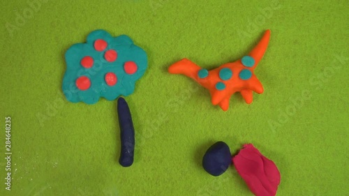 Soap bubbles are running on a acid green background with multicolred funny clay figurine of an orange dinosaur and blue tree  FDV photo