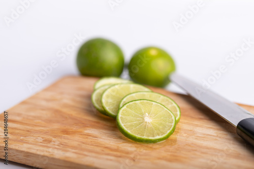 sliced of the green lime and seed with a knife place on wooden board