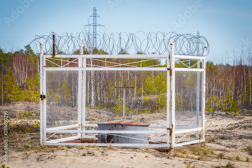 Fenced oil compressor with an iron fence and barbed wire mounted on the sand outside the city in flattering area.
