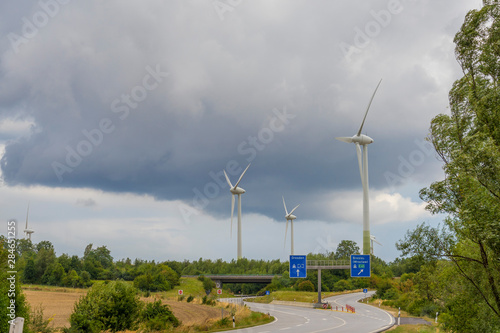 Wind turbines near highway under dramatic cloudy sky