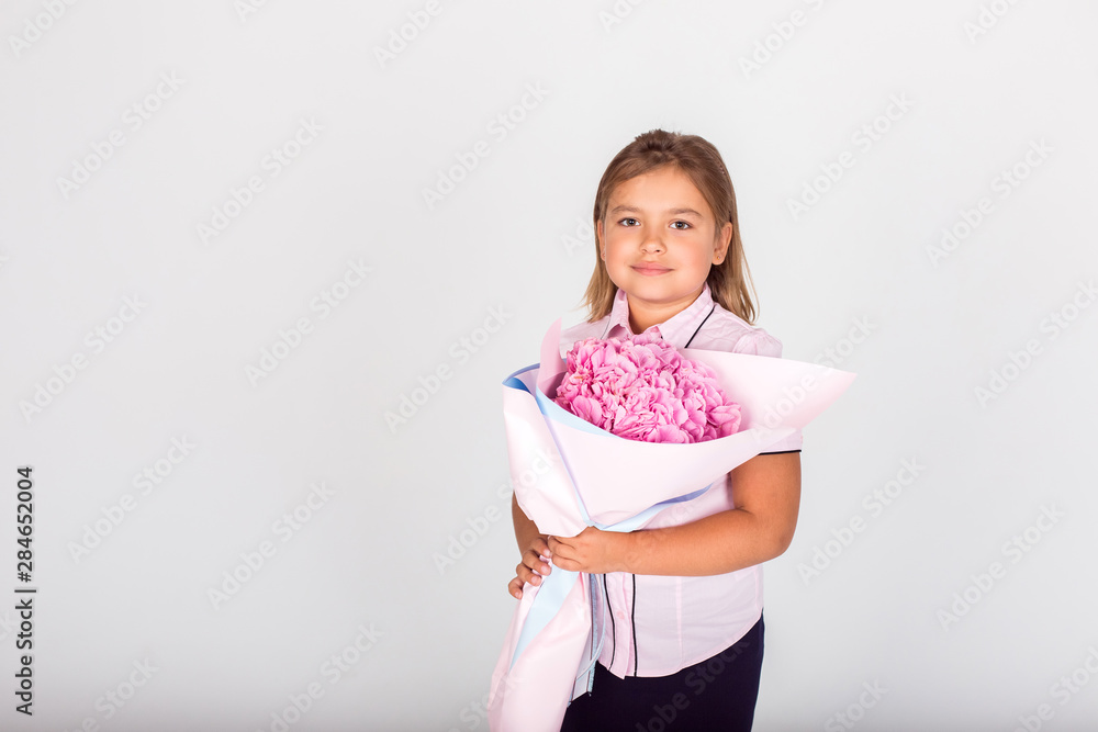 Cute adorable girl holding a bouquet of pink flowers for school teacher of lovely mom on isolated white background. Childhood, happiness, school concept Cute adorable girl holding a bouquet of pink flowers for school teacher of lovely mom on isolated white background. Childhood, happiness, school concept