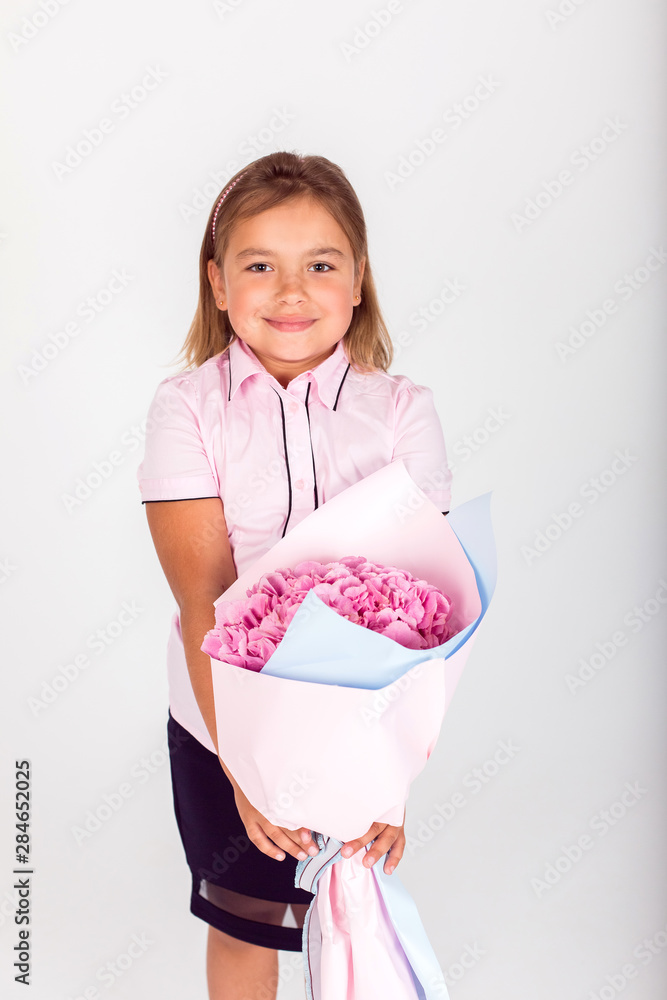 Cute adorable girl holding a bouquet of pink flowers for school teacher of lovely mom on isolated white background. Childhood, happiness, school concept Cute adorable girl holding a bouquet of pink flowers for school teacher of lovely mom on isolated white background. Childhood, happiness, school concept