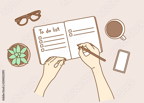 Opened personal organizer with a to do list. Top view of women hands writing goal to do list