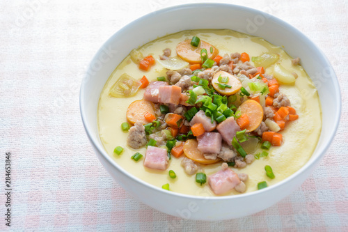 Steamed egg custard cuisine in a white bowl with minced pork, sausage and bacon. Or Only with egg, water, salt and some sesame oil, you can make this super smooth custard at home.