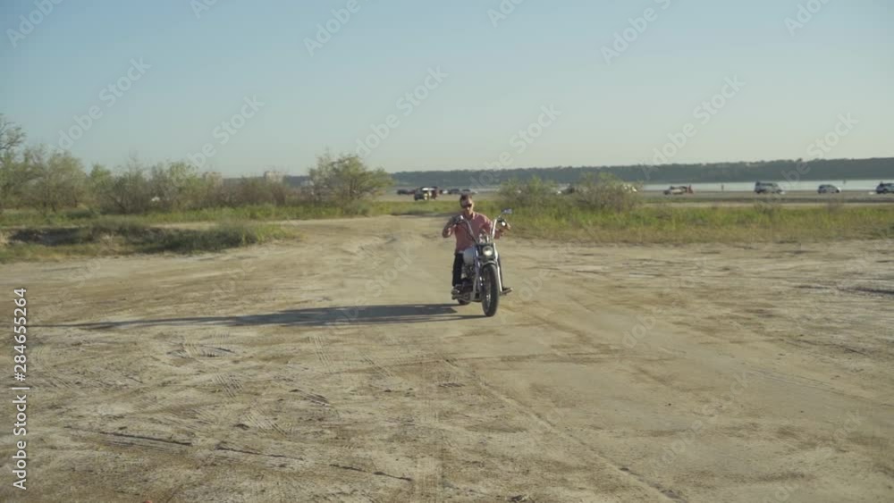 Motorcyclist driving his motorbike on the dirt road during sunset slow motion Motorcyclist driving his motorbike on the dirt road during sunset slow motion