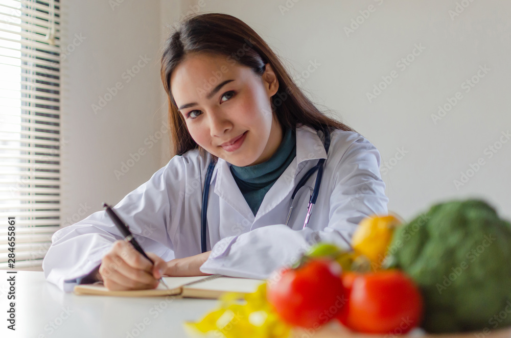 young nutritionist female doctor or medical looking at camera writing diet plan and fresh vegetables, fruits on desk at laboratory office, nutrition, healthy lifestyle, healthy food, dieting concept young nutritionist female doctor or medical looking at camera writing diet plan and fresh vegetables, fruits on desk at laboratory office, nutrition, healthy lifestyle, healthy food, dieting concept