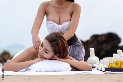 Beautiful asian woman enjoying spa massage therapy on the beach.