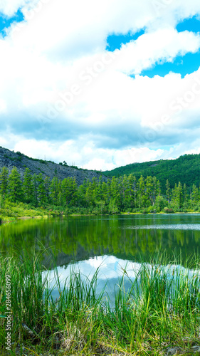 The ilent lake near green forest and cloudy sky photo