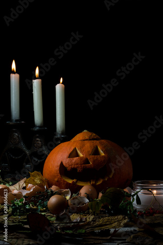 halloween jack-o-lantern pumpkin and candles on autumn leaves