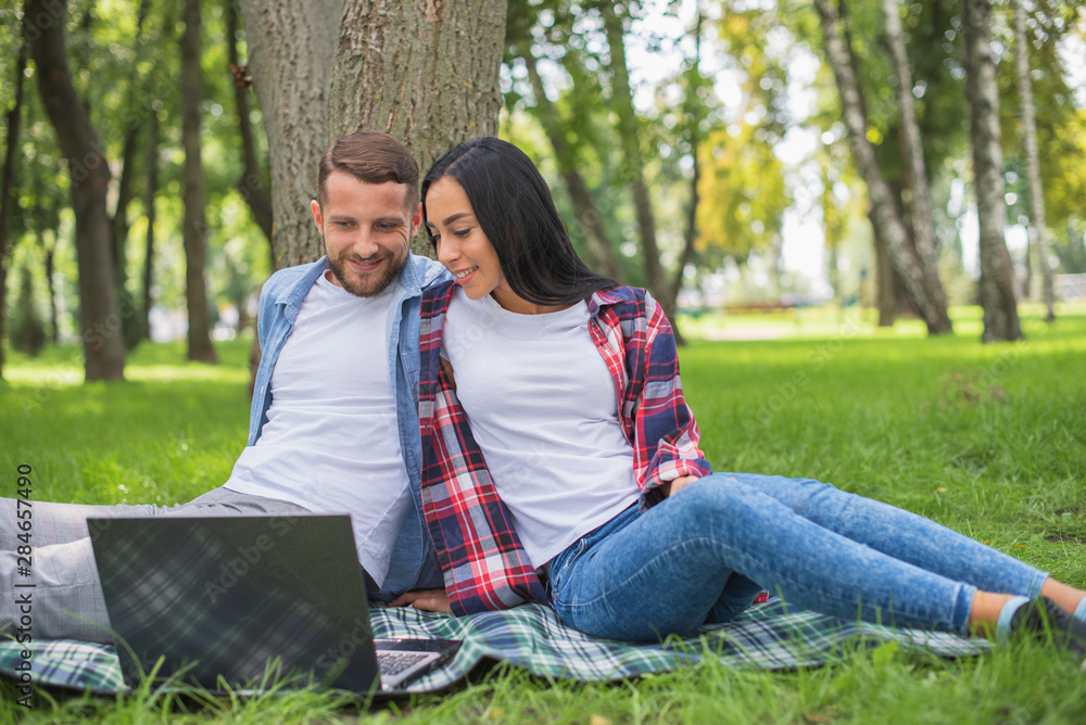 loving couple in the park are using a laptop, cuddling loving couple in the park are using a laptop, cuddling