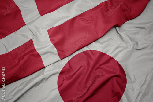 Photography waving colorful flag of japan and national flag of denmark.