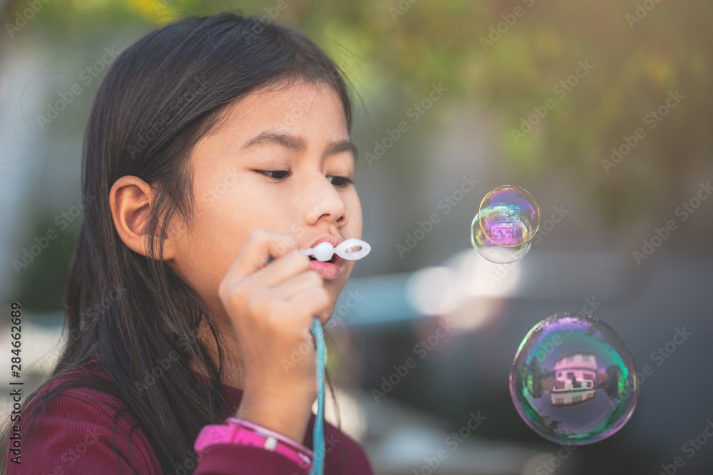 Cute little Asian girl playing soap bubbles at park, outdoors Cute little Asian girl playing soap bubbles at park, outdoors