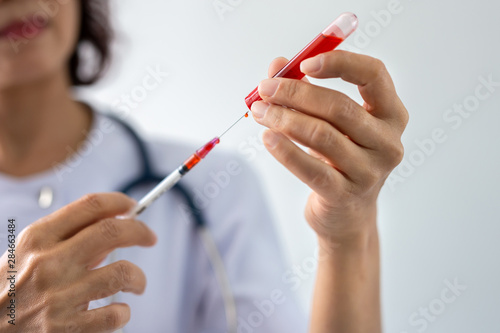 Female doctor with stethoscope holding syringe