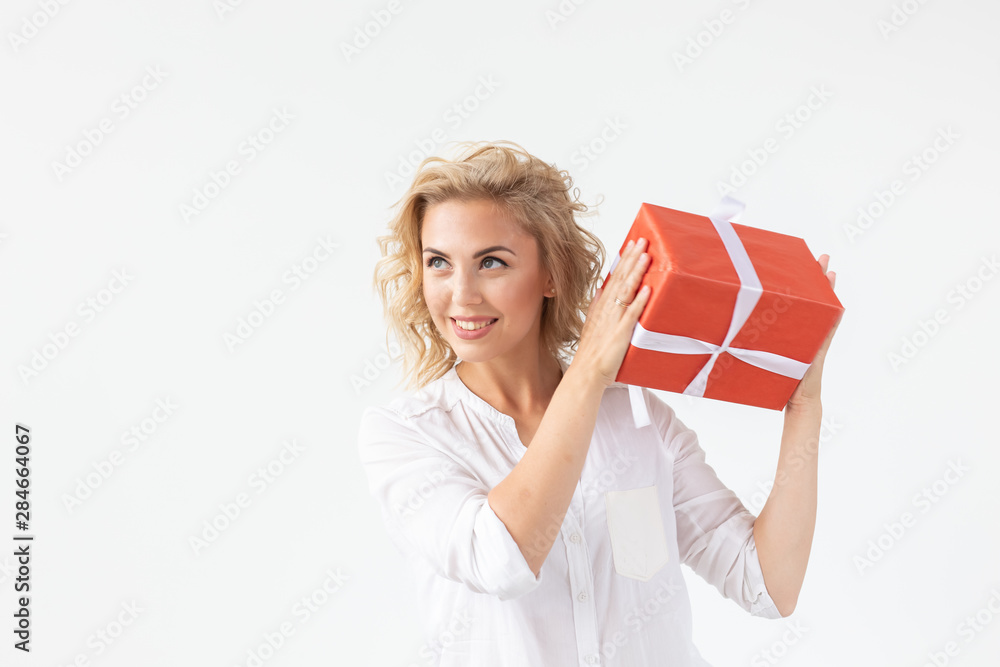 Holidays concept - Portrait of a smiling cute woman opening gift box isolated on a white background with copyspace Holidays concept - Portrait of a smiling cute woman opening gift box isolated on a white background with copyspace