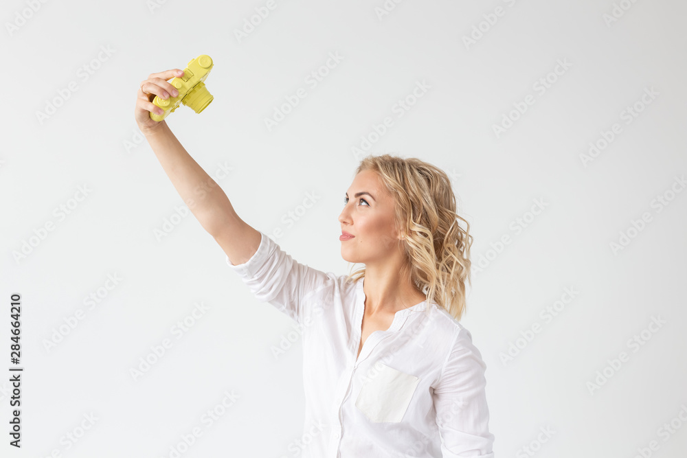 People, hobby and interests concept - Beautiful girl hold yellow retro camera on white background People, hobby and interests concept - Beautiful girl hold yellow retro camera on white background