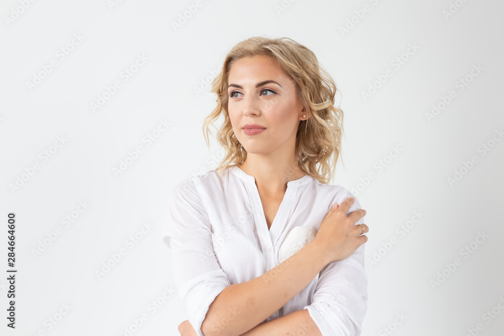 Smiling charming young blonde woman standing against a white background. Concept of carefree young girl Smiling charming young blonde woman standing against a white background. Concept of carefree young girl