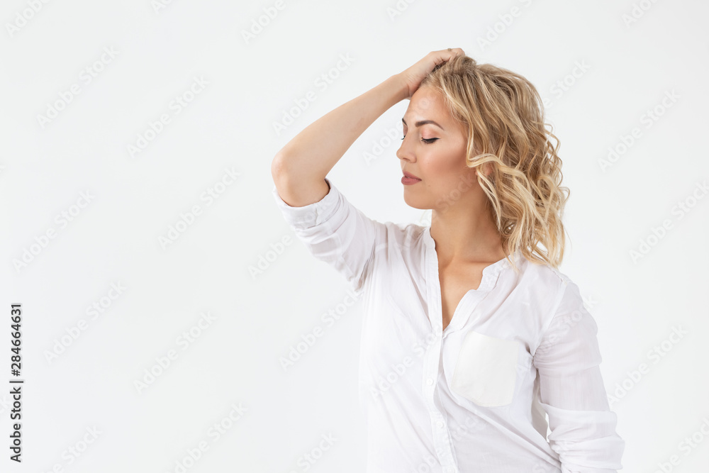 Cheerful young blond woman with long curly hair posing on a white background with copy space. The concept of a beautiful and well-groomed woman Cheerful young blond woman with long curly hair posing on a white background with copy space. The concept of a beautiful and well-groomed woman
