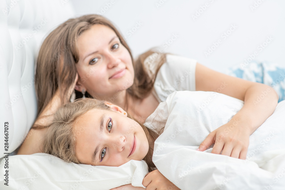 Mother and daughter lying together on the bed at home Mother and daughter lying together on the bed at home