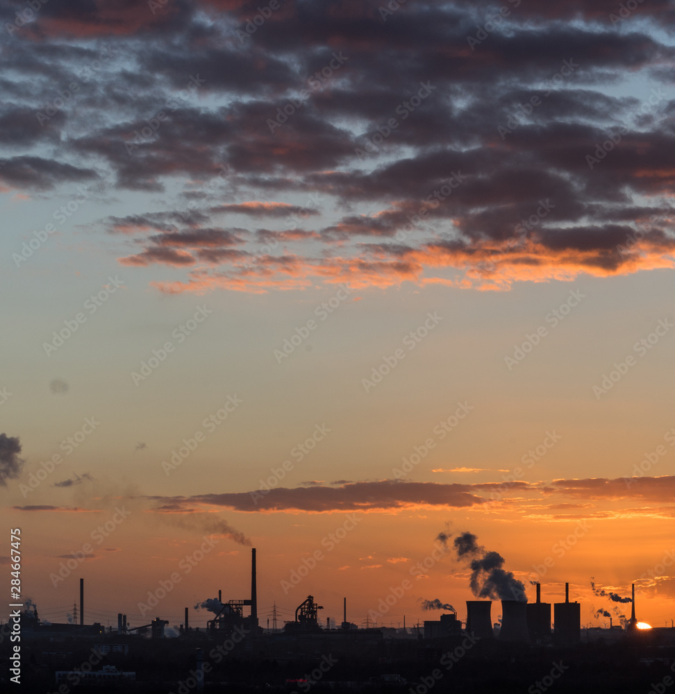 Naklejka premium Sonnenuntergang an der Sechs-Seen-Platte in Duisburg mit Blick auf die rauchenden Schlote am Horizont