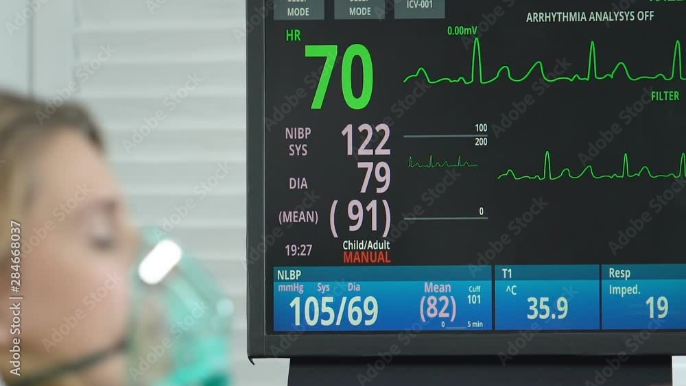 Female patient lying hospital bed with oxygen mask, monitor showing ...