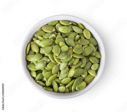 Pumpkin seeds nin white bowl isolated on white background. top view