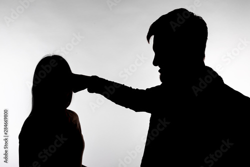 Domestic violence and abuse concept - Silhouette of man beating defenseless woman