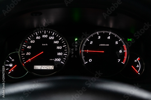 Car dashboard with white backlight: Odometer, speedometer, tachometer, fuel level, water temperature and more.