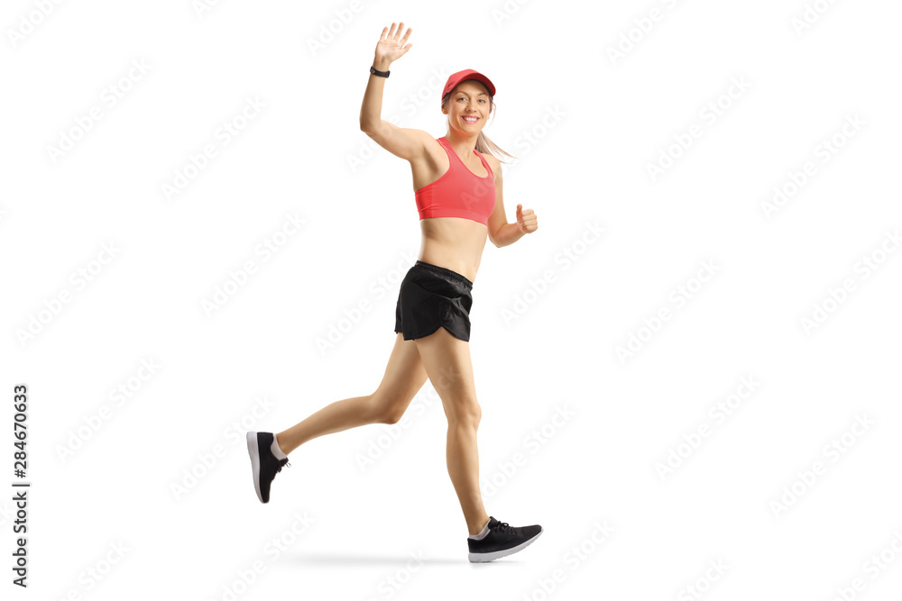 Young female in sportswear jogging and waving a the camera