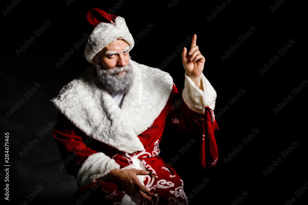 Obraz premium Portrait of a bad brutal mature Santa Claus showing middle finger signs, isolated on black background