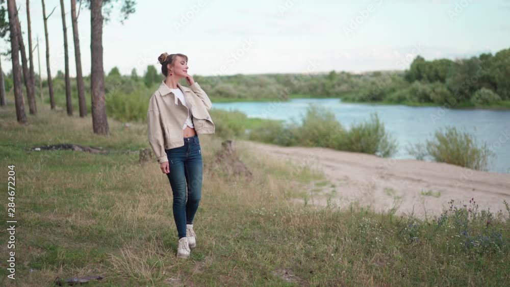 A young woman walks near the river and forest. A young woman walks near the river and forest.