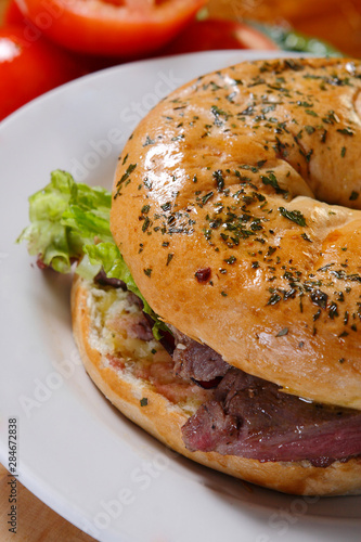 Bagel and croissant of ham, meat and lettuce with cherry tomatoes.