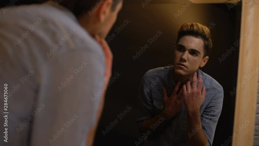 Upset gender fluid person looking in mirror and crying, self-identity problems Upset gender fluid person looking in mirror and crying, self-identity problems